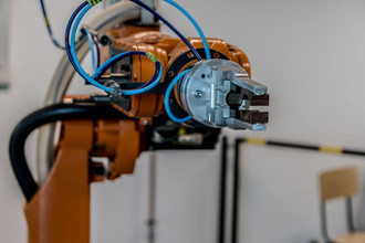 Orangener Roboterarm einer Industrieanlage