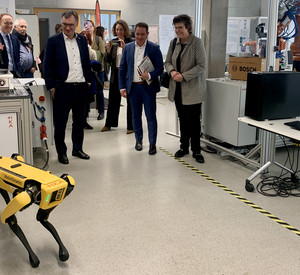 Gelber Roboter auf vier Beinen und Personen im Hintergrund